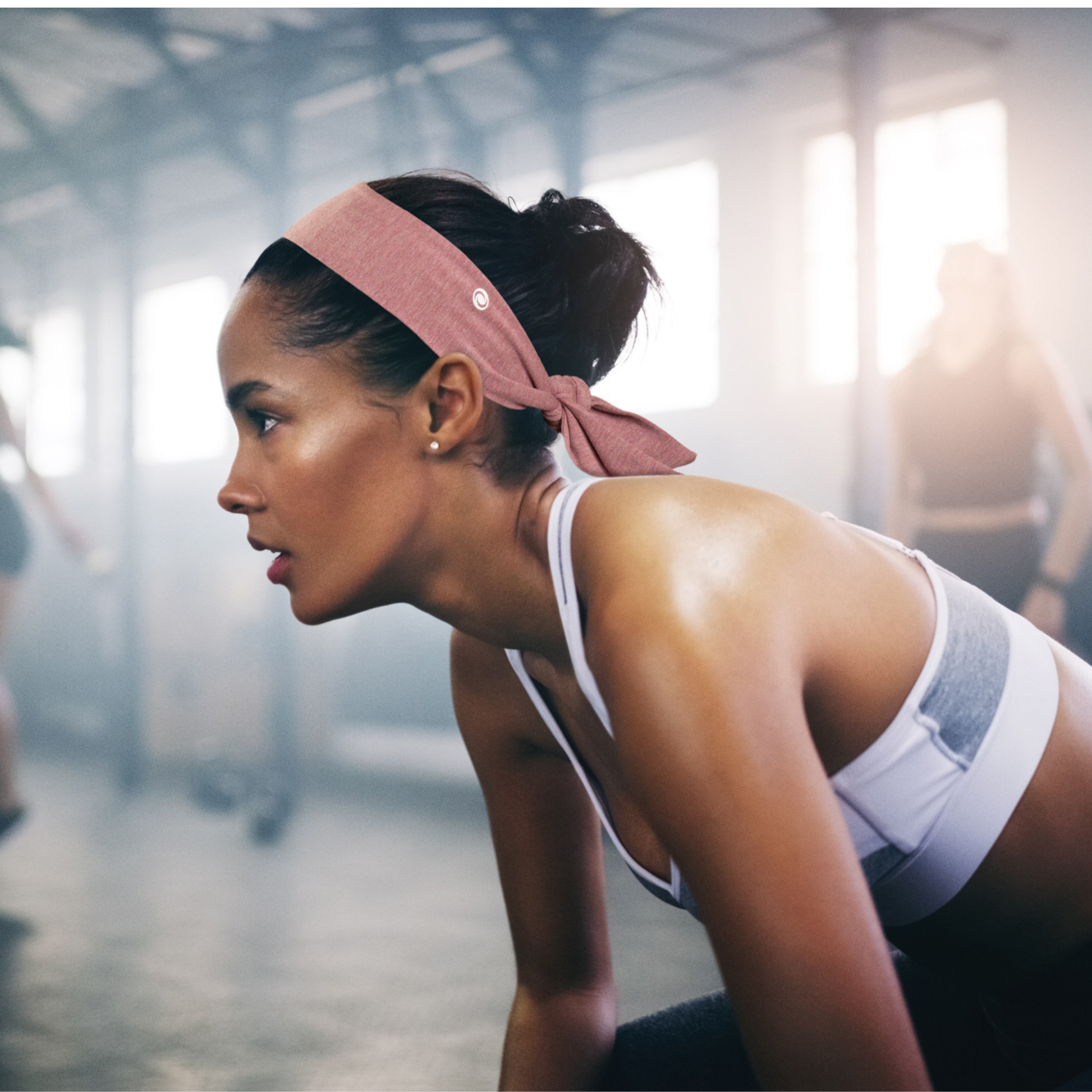 Woman in a gym wearing a SWAY headband resting from exercise 