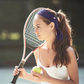 A woman playing tennis with her hair up and wearing a non-slip headband 